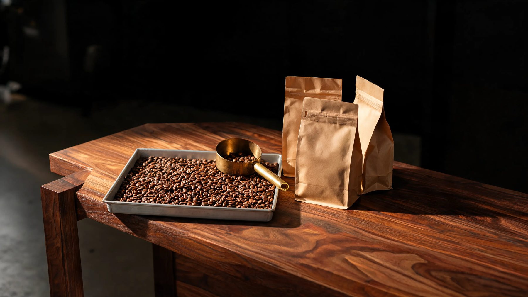 Roastery bench with a cooling tray of fresh beans and stacked kraft bags